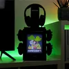 A gaming setup with a Minecraft-themed headset stand and controller holder, illuminated by green LED lights. Podgląd zdjęcia produktu