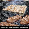 A smoking box filled with wood pellets sits on a grill above steaks, with smoke rising. Produktbild-Vorschau