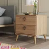 A bedside table with two drawers next to a bed, with a lamp and vase on top. Produktbild-Vorschau