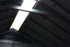 Interior view of a dark-colored structure, possibly a shed or outbuilding, with a skylight providing illumination. Produktbild-Vorschau