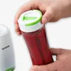 A hand is holding a blender cup filled with red liquid, with a blender base visible on the left. Produktbild-Vorschau