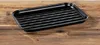 A black grill pan sits on a wooden surface. Produktbild-Vorschau
