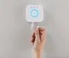 A hand is plugging a network cable into a white Philips Hue bridge device mounted on a light gray wall. Produktbild-Vorschau