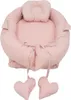 A pink baby nest with a headrest and two heart-shaped pillows hanging from ties. Produktbild-Vorschau