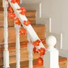 A string of decorative lights shaped like autumn leaves is draped along a white banister of a wooden staircase. Náhled obrázku produktu