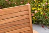 A close-up view of a wooden garden bench with a blurred background of flowers and greenery. Produktbild-Vorschau