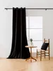 A black velvet curtain hangs on a rod in front of a window, with a small wooden table and chair to the side. Produktbild-Vorschau