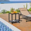 A black metal side table with drinks and snacks sits on a wooden deck next to a swimming pool, with a lounge chair and ocean view in the background. Produktbild-Vorschau