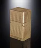 A gold-colored lighter with a textured surface sits on a reflective black surface with a gradient gray background. Produktbild-Vorschau