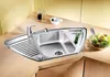 A modern stainless steel corner sink with a faucet, a drying rack, and a small compartment for herbs. A bowl of salad is placed on the countertop next to the sink. Náhľad obrázku produktu
