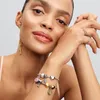A woman wearing jewelry, including bracelets with charms and rings, and earrings. Podgląd zdjęcia produktu