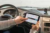 A person's hands are shown interacting with a GPS navigation device mounted on the dashboard of a truck. Produktbild-Vorschau