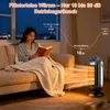 A woman is reading a book on a couch while a space heater is operating in the foreground, emitting warm air. Produktbild-Vorschau
