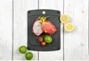 A black cutting board with dragon fruit, strawberries, limes, and lemons on a white wooden background. Náhľad obrázku produktu