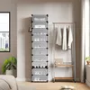 A tall, narrow shoe rack with multiple transparent drawers is shown in a room, next to a clothing rack with hanging garments. A window with a city view is visible on the left. Voir les images du produit