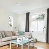 A living room with a sofa, coffee table, and window. Produktbild-Vorschau