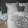 A neatly made bed with striped bedding and a small grey cushion. Anteprima dell’immagine prodotto