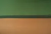 A close-up view of a stitched seam on a fabric product, divided into green and tan sections. Podgląd zdjęcia produktu