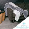 A gray and white sherpa blanket draped over a dark brown couch. Anteprima dell’immagine prodotto