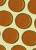 A top-down view of multiple round containers filled with a brown substance, arranged in a grid pattern on a light yellow background. Produktbild-Vorschau
