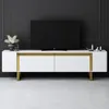 A white and gold TV stand with a black television on top, set against a dark gray wall. Náhľad obrázku produktu