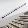 A black metal handrail is mounted on a white wall next to a modern staircase with illuminated steps. Produktbild-Vorschau