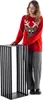 A woman in a Christmas sweater stands next to a black metal firewood rack. Náhled obrázku produktu