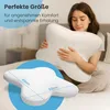 A woman is holding a white butterfly-shaped pillow in a bedroom setting. A close-up inset shows the pillow's dimensions. Produktbild-Vorschau