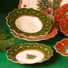 A close-up view of Christmas-themed plates with a green background and pine branches. Anteprima dell’immagine prodotto
