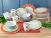 A collection of floral-patterned ceramic dinnerware, including plates, bowls, and mugs, arranged on a wooden surface with a blue background. Produktbild-Vorschau