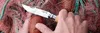 A close-up of a hand holding a knife and cutting a fishing net with an orange float caught in it. Náhled obrázku produktu