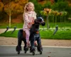 A young girl rides a black toy horse with wheels in a park. Anteprima dell’immagine prodotto