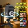 A window projector with a tripod stand is shown in the foreground, with a Christmas tree and a blurred interior in the background. A grid of small images showing different movie scenes is displayed to the right. Náhled obrázku produktu