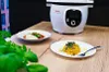 A Tefal Cook4me+ smart multi-function cooker is shown on a wooden table, with two plates of food in front of it and some greenery in the foreground. Podgląd zdjęcia produktu