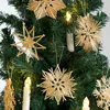 Straw star ornaments hanging on a Christmas tree with lights. Produktbild-Vorschau