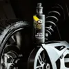 A bottle of K2 APC STRONG PRO cleaner is placed on a motorcycle's wheel and suspension system. Náhled obrázku produktu
