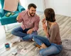 A couple playing cards on the floor in a living room. Produktbild-Vorschau