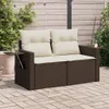 A brown poly rattan garden sofa with beige cushions is placed on a paved patio in front of a wooden fence. Podgląd zdjęcia produktu
