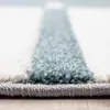 A close-up, low-angle view of a rug with a textured surface and a striped pattern. Voir les images du produit