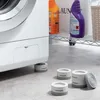 A washing machine is shown with anti-vibration feet installed, and extra feet are placed on the floor nearby. Cleaning supplies are visible on a shelf in the background. Anteprima dell’immagine prodotto