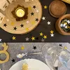A table setting decorated with star confetti and a lit candle. Produktbild-Vorschau