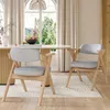 Two dining chairs are placed around a dining table in a well-lit room with large windows. Voir les images du produit