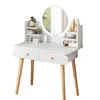 A white vanity table with wooden legs, featuring a round mirror and shelves stocked with various cosmetic products. Produktbild-Vorschau