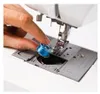 A close-up view of a person's hand inserting a blue bobbin into a sewing machine. Anteprima dell’immagine prodotto