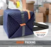 A person is packing a cube-shaped item with a blue moving blanket and tape. Anteprima dell’immagine prodotto