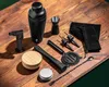 A collection of black bartending tools laid out on a wooden surface. Voir les images du produit