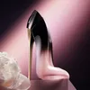 A perfume bottle shaped like a high-heeled shoe, with a white flower in the foreground and a gradient pink and dark background. Náhľad obrázku produktu