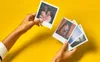 Two hands holding and displaying Polaroid photos against a bright yellow background. Podgląd zdjęcia produktu