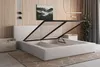 A bedroom scene featuring a bed with its storage compartment open, a nightstand, and wall art. Produktbild-Vorschau