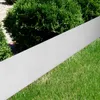A silver metal garden edging strip is placed diagonally across a lawn, with green bushes in the background. Produktbild-Vorschau
